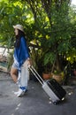 Asian woman wearing indigo art clothes for show and portrait with luggage at garden