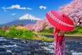 Asian woman wearing japanese traditional kimono and looking at cherry blossoms with fuji mountains in Shizuoka, Japan