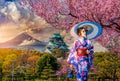 Asian woman wearing japanese traditional kimono at Osaka Castle and full cherry blossom, with Fuji mountain background, Japan Royalty Free Stock Photo