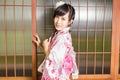 Asian woman wearing a kimono in front of Japanese wooden windows