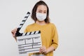 An Asian woman wearing a mask is holding a film clapper board. Royalty Free Stock Photo