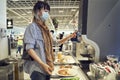 Asian woman wearing mask making herself a coffee at buffet during pandemic