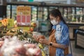 Asian woman wearing protect face mask and  shopping fruit, vegetable in grocery department store Royalty Free Stock Photo