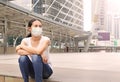 Asian woman wearing protective mask to protect virus, pollution and the flu sitting at public area Royalty Free Stock Photo