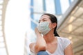 Asian woman wearing protective mask to protect virus, pollution and the flu sitting at public area Royalty Free Stock Photo