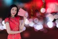 Asian woman wearing red traditional dress holding red pocket with the chinese new year festival background with lanterns