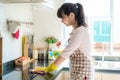 Asian woman wearing rubber protective gloves cleaning kitchen cupboards in her home during Staying at home using free time about Royalty Free Stock Photo