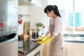 Asian woman wearing rubber protective gloves cleaning kitchen cupboards in her home during Staying at home using free time about Royalty Free Stock Photo