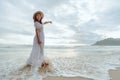 Asian woman wearing stylish hat and clothes pointing at the sky and looking to the ocean and enjoying beautiful sunset on the Royalty Free Stock Photo