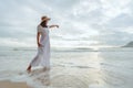 Asian woman wearing stylish hat and clothes pointing at the sky and looking to the ocean and enjoying beautiful sunset on the Royalty Free Stock Photo