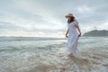 Asian woman wearing stylish hat and clothes walking on the beach and enjoying beautiful nature in the sunset time. Royalty Free Stock Photo