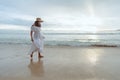 Asian woman wearing stylish hat and clothes walking on the beach and enjoying beautiful nature in the sunset time. Royalty Free Stock Photo