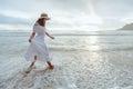 Asian woman wearing stylish hat and clothes walking on the beach and enjoying beautiful nature in the sunset time. Royalty Free Stock Photo