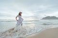 Asian woman wearing stylish hat and clothes walking on the beach and enjoying beautiful nature in the sunset time. Royalty Free Stock Photo