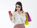 Asian woman wearing sunglasses, holding colorful paper bags, mobile phone, presenting  online shopping, cashless payment by Royalty Free Stock Photo