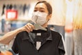 Asian woman wearing surgical mask and choosing the red t-shirt clothes and looking to mirror in mall or clothing store Royalty Free Stock Photo