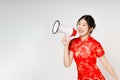 Asian woman wearing traditional cheongsam qipao dress with gesture holding megaphone isolated on white background. Happy Chinese Royalty Free Stock Photo