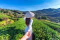 Asian woman wearing Vietnam culture traditional holding man`s hand and leading him to green tea field. Royalty Free Stock Photo