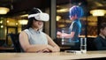 Asian woman wearing VR headset communicates with cartoon character via hologram