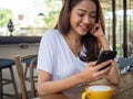 An Asian woman wearing a white shirt sitting in a telephone in a coffee shop. Happy time Royalty Free Stock Photo