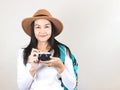 Asian woman wearing  white t-shirt and hat , holding camera and carrying backpack, smiling and looking at camera. Travelling Royalty Free Stock Photo