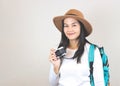 Asian woman wearing  white t-shirt and hat , holding camera and carrying backpack, smiling and looking at camera. Travelling conce Royalty Free Stock Photo