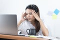 Asian woman wearing a white T-shirt Working at home With serious emotions and thinking power, and hands are holding their heads