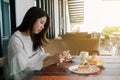 Asian woman wearing in white taking a photo of the bakery With mobile phones Smiling happily in the warm ambiance at the out door