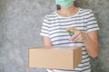 Asian woman wears mask using spray alcohol sanitizer cleaning parcel post, to prevent the virus and bacterias from postal sender,