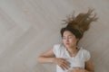 Asian woman wears white t-shirt lie on the wooden floor exhaustedly.