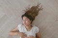 Asian woman wears white t-shirt lie on the wooden floor exhaustedly.