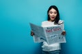 Asian woman in white blouse reading newspaper with fake news on blue background Royalty Free Stock Photo