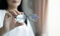 Asian woman in white coat holds glasses in her hands. Vision diagnostics by an optometrist concept