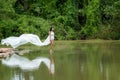 Asian woman with white dress relaxing and standing at tropical exotic river with turquoise amazing color water in beautiful destin