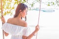 Asian woman on white dress sitting on swing at beach. People and Royalty Free Stock Photo