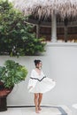 Asian woman in white light tunic, barefoot. Casual style, tropical garden. Royalty Free Stock Photo