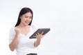 Asian woman in white shirt is smiling happily and satisfy while look at on tablet in her hand on white background