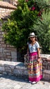 Asian woman in white t-shirt  in Athens in white hat and sarong leaning on stone wall in front of church Royalty Free Stock Photo