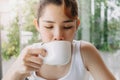 Woman in white tank top is drinking hot drink in the cup. Royalty Free Stock Photo