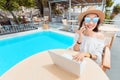 Asian woman wirking with mobile phone and laptop pc and relaxing near swimming pool. Distant work concept Royalty Free Stock Photo