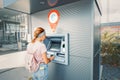 Woman withdraws money and pays the credit for study at the street European ATM self-service macine Royalty Free Stock Photo