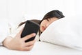 Asian Woman woke up by smartphone alarm clock and turning off snoozing phone alarm clock.