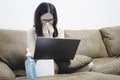 Asian woman work at home and use tissue or napkins close her nose while cough or sneeze. Her lap had a laptop computer placed and Royalty Free Stock Photo