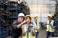 Asian woman worker with safety vest and helmet holds tablet, reports information to her supervisor senior foreman at manufacturing Royalty Free Stock Photo