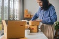 Asian woman worker or seller packing cardboard ecommerce shipping order box for dispatching