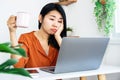 Asian woman worker tired from overworked hand holding cup of coffee looking at laptop feeling sleepy and bored with working Royalty Free Stock Photo