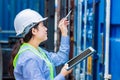 Asian woman worker in warehouse using tablet computer to check cargo control goods order in inventory warehouse Royalty Free Stock Photo