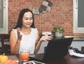 Asian woman working with computer laptop in the kitchen, using laptop for video chatting Royalty Free Stock Photo