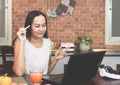 Asian woman working with computer laptop in the kitchen, using laptop for video chatting Royalty Free Stock Photo