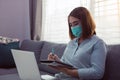 Asian woman working from home at a laptop computer during a coronavirus epidemic by quarantine and wearing medical masks Royalty Free Stock Photo